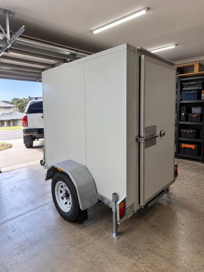 Low profile coolroom trailer with its door open, parked in a garage to show it fits under a standard roller door