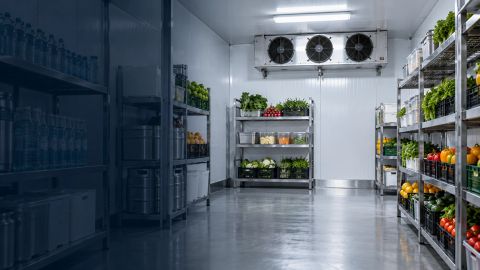 Inside a commercial walk-in coolroom, with evaporator fans above the stocked shelving